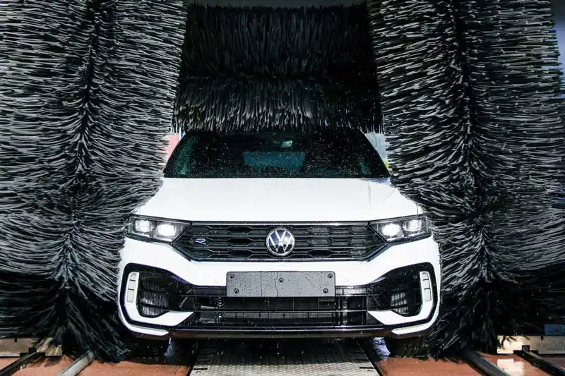 Zu sehen ist ein weißes VW Auto in der Waschanlage.